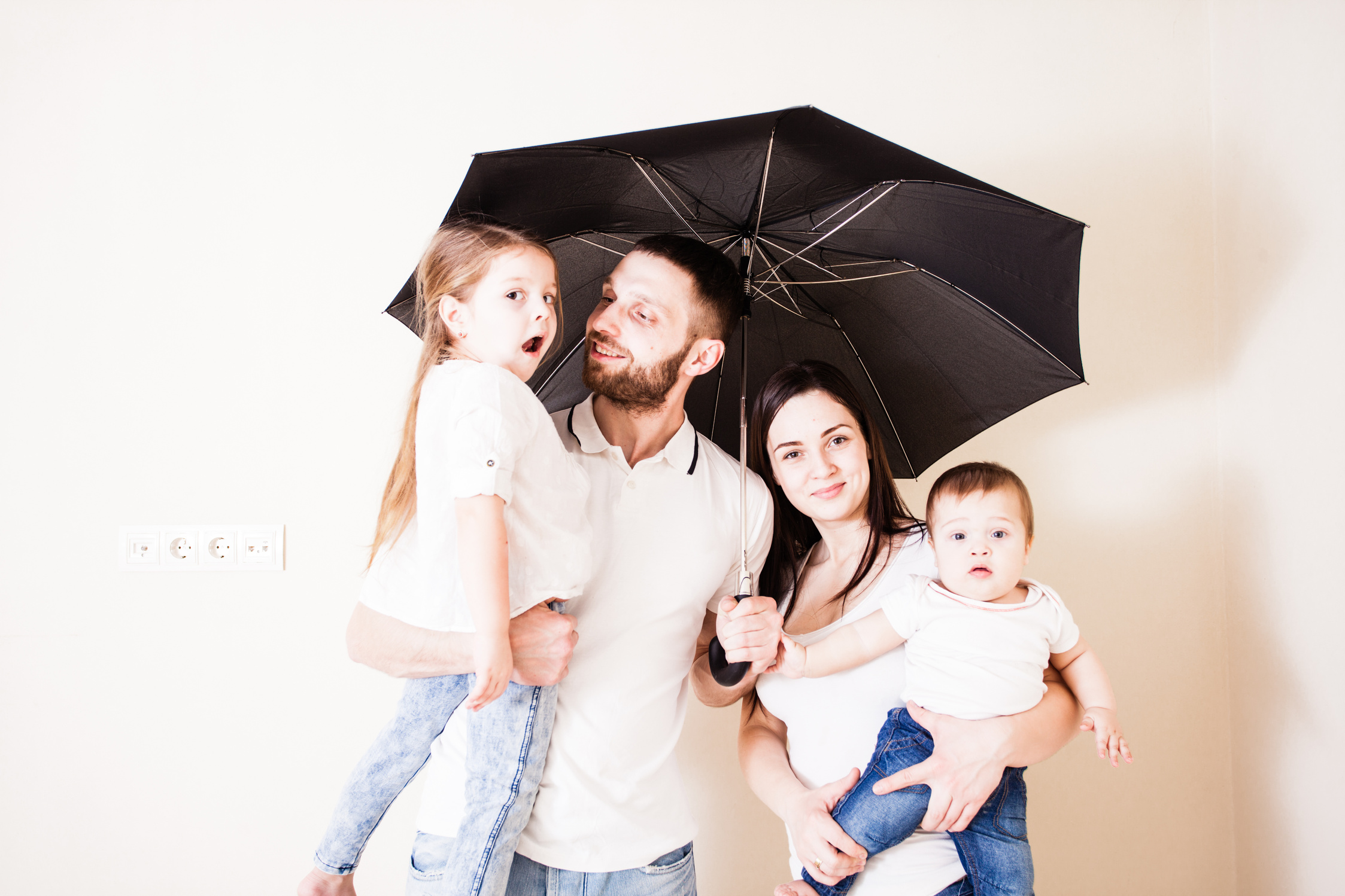 Happy Family Feeling Safe under Umbrella